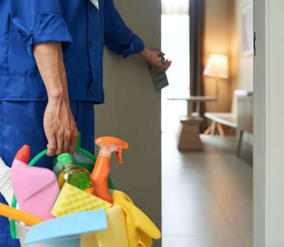Time for room cleaning Professional cleaner with bucket of detergents opening room