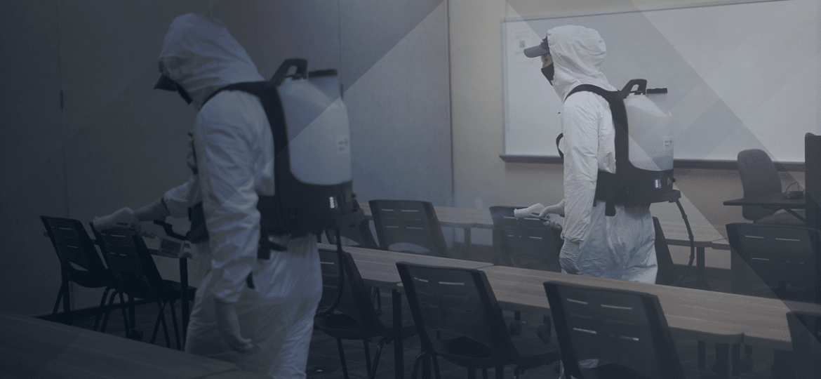 Two men in PPE suits spraying the room